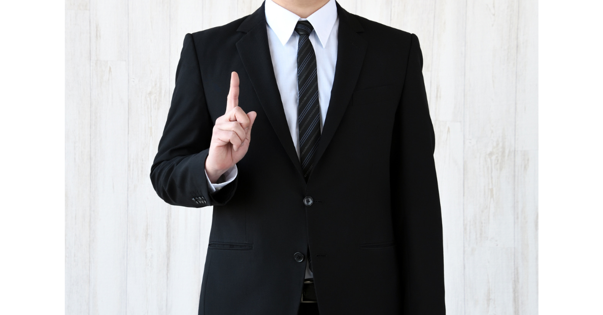 スーツを着た男性が指を立ててなぜかを説明している