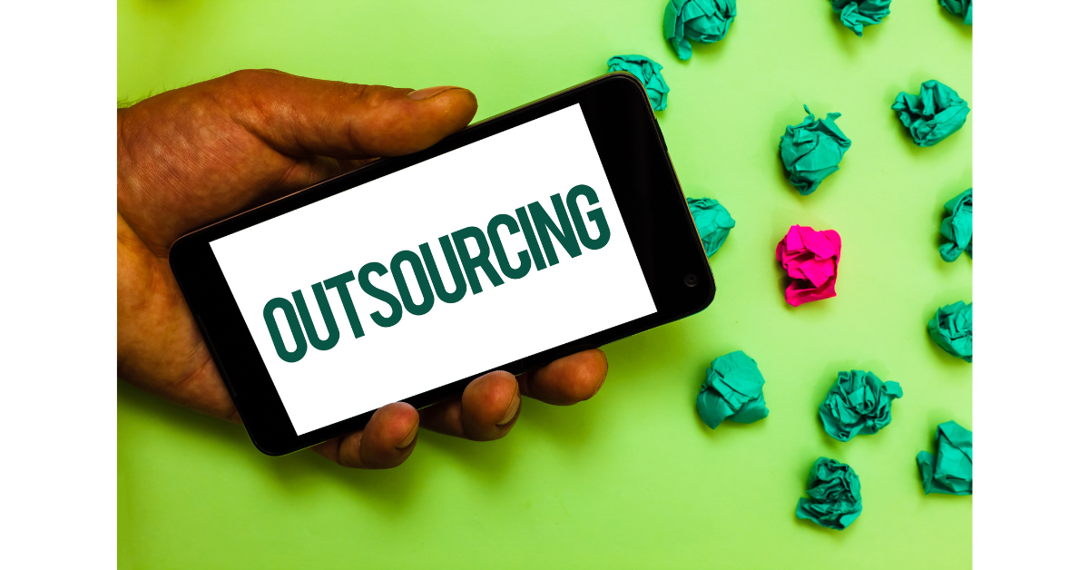 緑色の背景にスマホの画面に「OUTSOURCING(外注)」と映っている