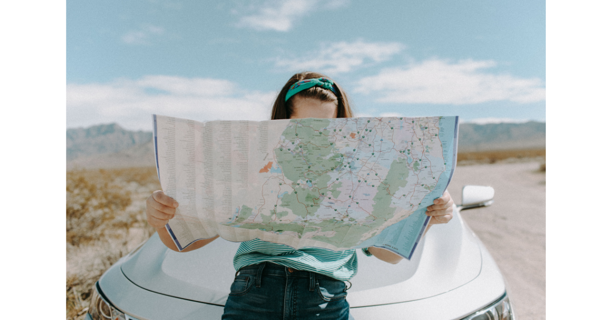 車に腰かけてイラストのマップを読む人