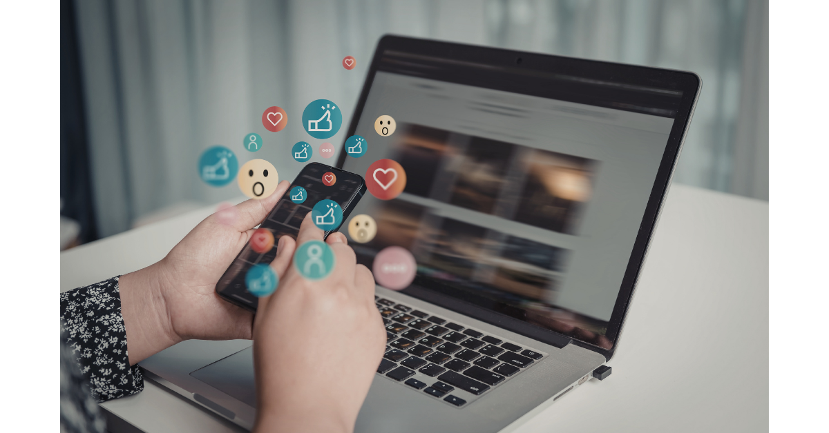 パソコンの前でスマートフォンでSNSを見ている人